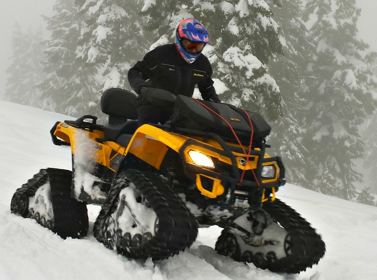 rider going down hill on snowtracked ATV
